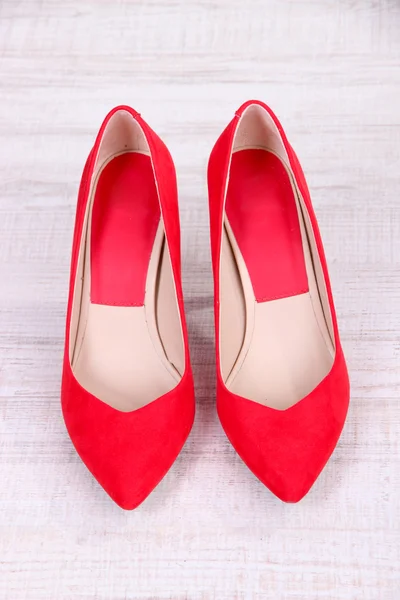 Hermosos zapatos femeninos rojos, sobre fondo de madera — Foto de Stock