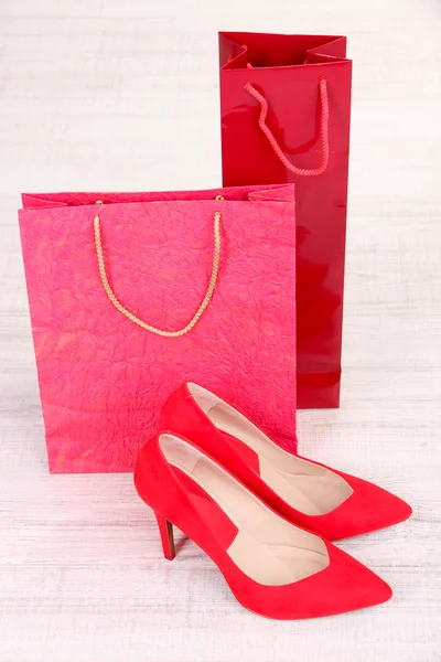 Belles chaussures féminines rouges et sacs de magasin — Photo