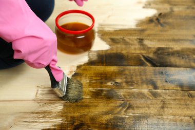Parlak arkaplanda, ahşap çitlere koruyucu cila uygulanıyor