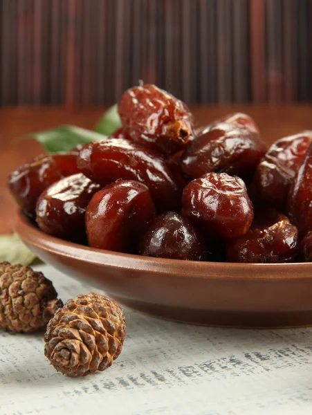 Dried dates on plate with bumps on table on bamboo background — Stock Photo, Image