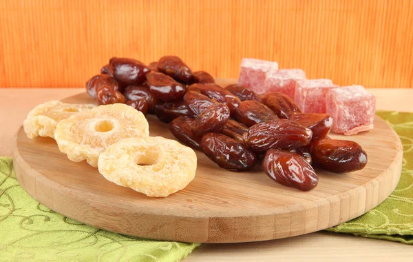 Dried dates with candied pineapples and Turkish delights on table on bamboo background — Stock Photo, Image