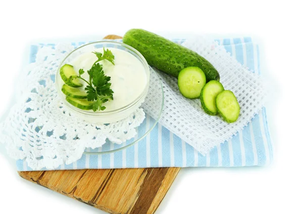 Salatalık üzerinde ahşap masa, üzerinde beyaz izole kase yoğurt — Stok fotoğraf