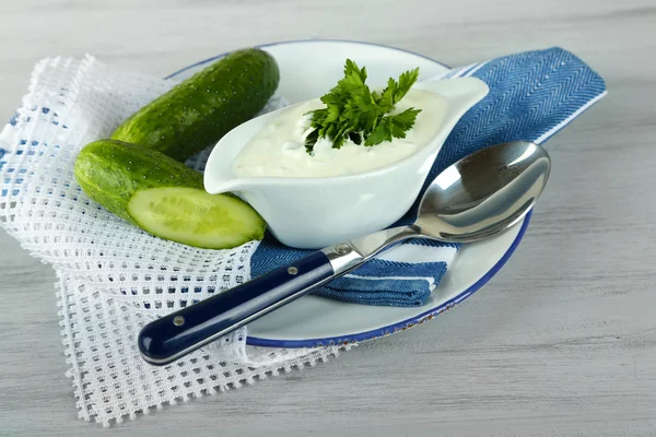 Yogurt al cetriolo in salsa, su tovagliolo di colore, susfondo di legno color — Foto Stock