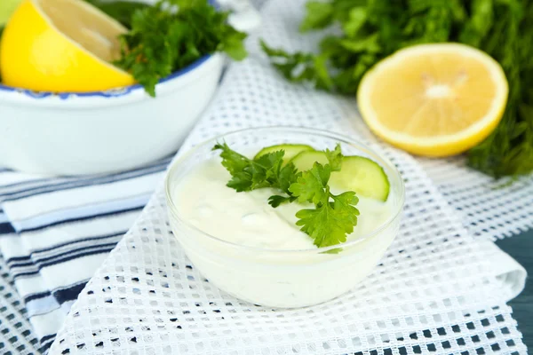 Yogur de pepino en un tazón de vidrio, en una servilleta de color, sobre un fondo de madera —  Fotos de Stock