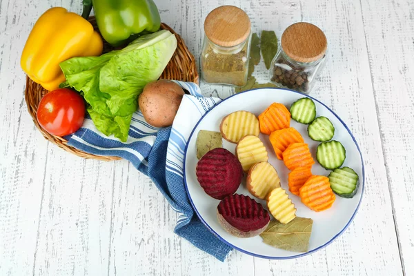 Hermosas verduras en rodajas, en plato, sobre fondo de madera — Foto de Stock