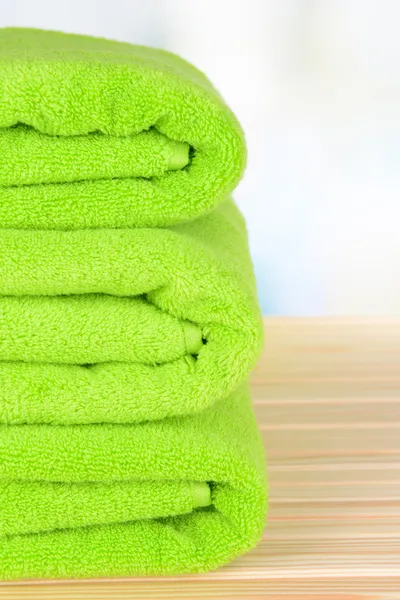 Zielone ręczniki na stole na jasnym tle — Zdjęcie stockowe