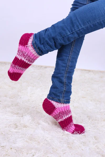 Patas femeninas y calcetines de colores sobre fondo de alfombra blanca —  Fotos de Stock