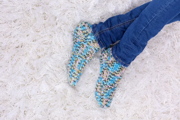 Female legs in blue jeans trousers and colorful socks on white carpet background — Stock Photo, Image