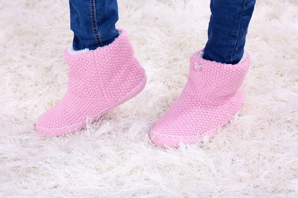 Pernas femininas em calças jeans azuis e sapatos de inverno em casa, no fundo do tapete branco — Fotografia de Stock