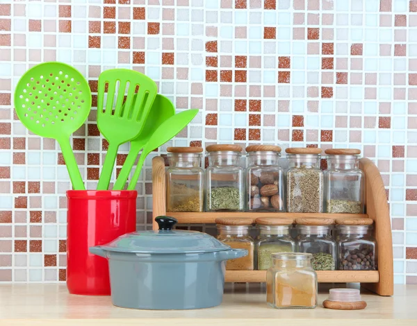 Set van specerijen, vaatwerk en keukengerei in keuken op tafel op mozaïek tegels achtergrond — Stockfoto