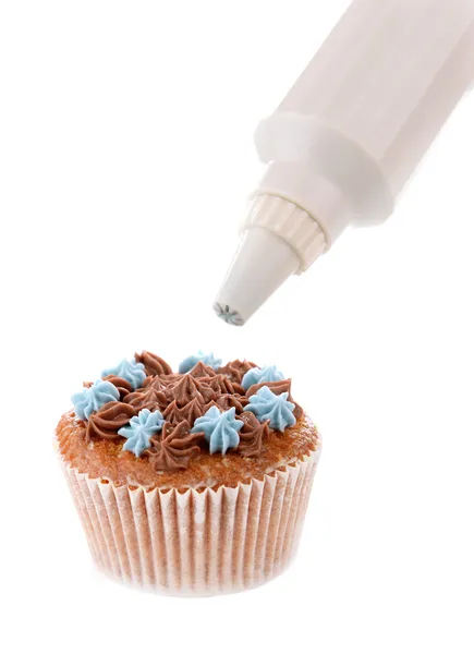 Banketbakker versieren smakelijke cupcake met boter room, geïsoleerd op wit — Stockfoto