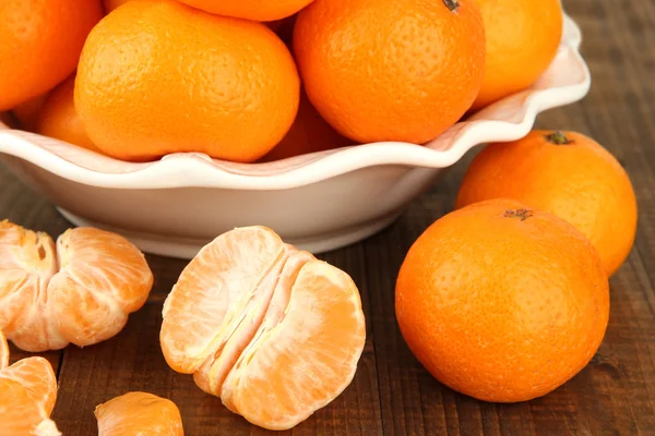 Tangerinas maduras em tigela no fundo de madeira — Fotografia de Stock