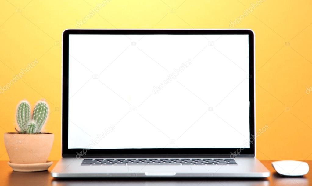Laptop and cactus in flowerpot on wooden table on yellow background