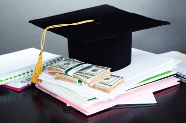 Mezuniyet veya gri arka plan üzerinde ahşap masa üzerinde eğitim için para