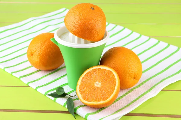 Citrus press and ripe oranges on green wooden table — Stock Photo, Image