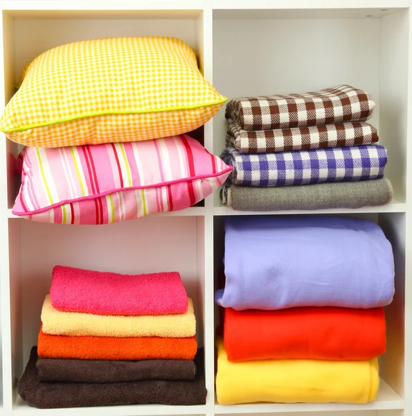 Luminosi cuscini, asciugamani e plaid sugli scaffali, isolati su bianco — Foto Stock