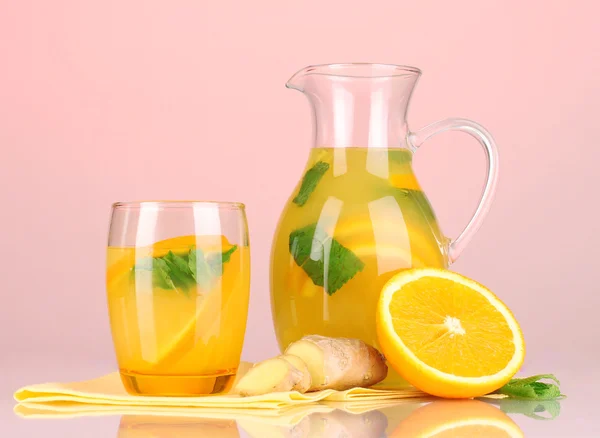 Limonata arancione in brocca e vetro su fondo rosa — Foto Stock