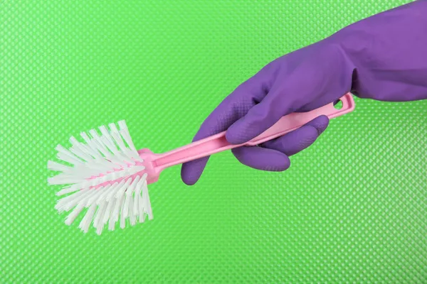 Toilet brush in hand on green background — Stock Photo, Image