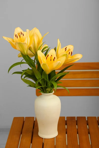 Beautiful orange lilies in vase on wooden table — Stock Photo, Image