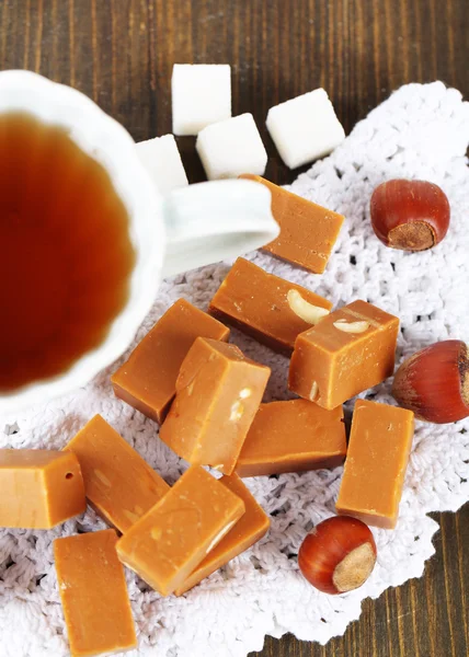 Vele toffee en kopje thee op servet op houten tafel — Stockfoto