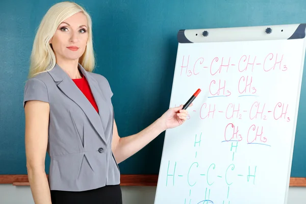 School teacher near whiteboard on blackboard background — Stock Photo, Image