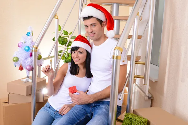 Pareja joven celebrando Año Nuevo en un nuevo hogar en el fondo de las escaleras —  Fotos de Stock