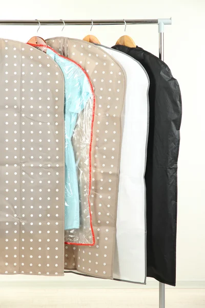 Clothes in cases for storing on hangers, on gray background — Stock Photo, Image
