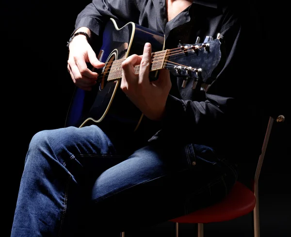 Joven músico tocando guitarra acústica y cantando, sobre fondo oscuro — Foto de Stock