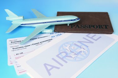 Açık mavi arka planda pasaportlu uçak biletleri.