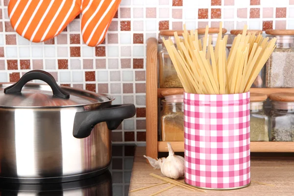 Pot on stove in kitchen on table on mosaic tiles background — Stock Photo, Image