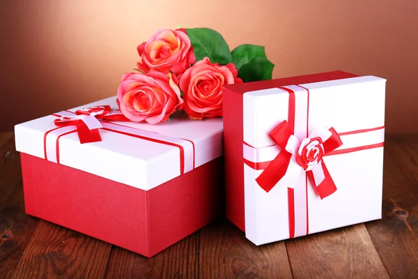 Caixas de presente bonitas com flores na mesa sobre fundo marrom — Fotografia de Stock