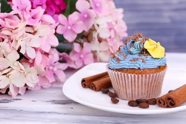 Smakelijke cupcake met boter room, op de plaat, op een houten achtergrond kleur — Stockfoto