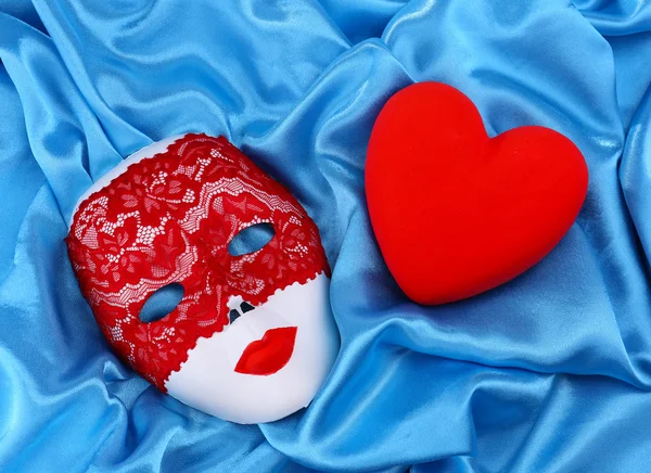 Cuore rosso decorativo e maschera, su sfondo tessuto a colori — Foto Stock