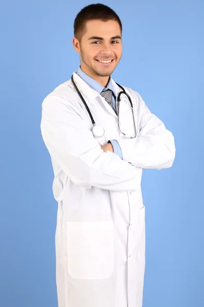 Médico masculino de pé com pasta, no fundo azul — Fotografia de Stock