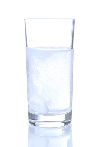 Glass with efervescent tablet in water with bubbles isolated on white