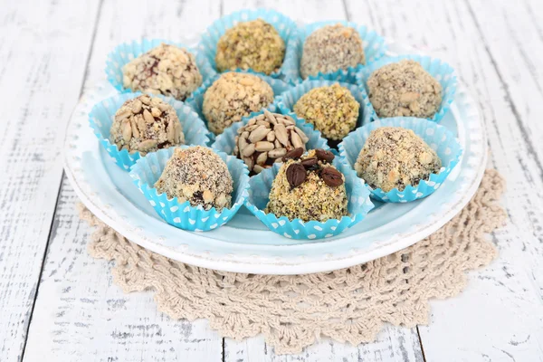 Set of chocolate candies, on plate, on wooden background — Stock Photo, Image