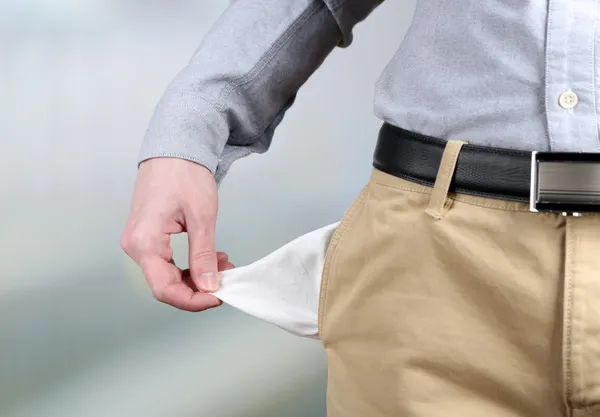 Mann zeigt seine leere Tasche auf hellem Hintergrund — Stockfoto