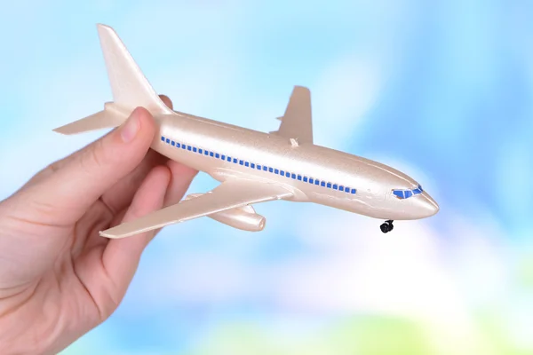 明るい青の背景に手でおもちゃの飛行機 — ストック写真