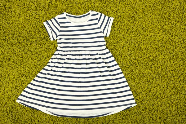 Schönes Kleid für kleines Mädchen auf grünem Teppich — Stockfoto