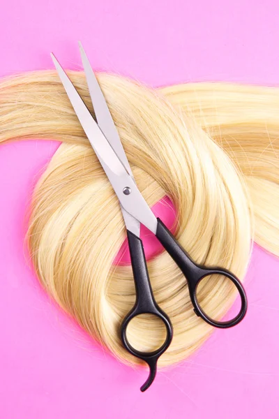 Long blond hair with scissors on pink background — Stock Photo, Image