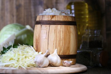 Composition with fresh and marinated cabbage (sauerkraut) in wooden barrel, on wooden table background clipart
