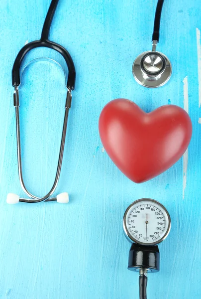 Tonometer, stethoscope and heart on wooden table close-up — Stock Photo, Image