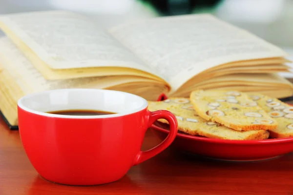 Tasse Kaffee mit Keksen und Buch auf Holztisch vor hellem Hintergrund — Stockfoto