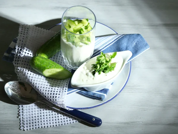 Cucumber yogurt in glass, on color napkin, on wooden background — Stock Photo, Image