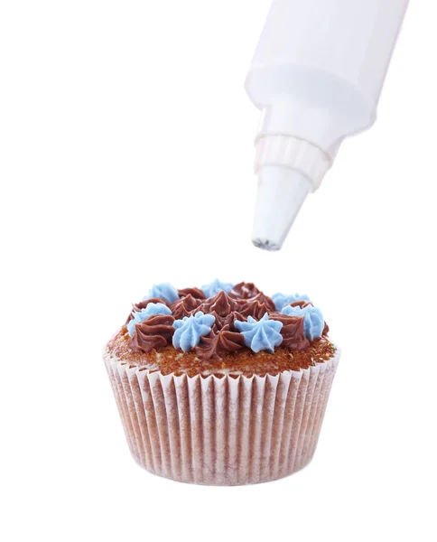 Pastelería decorando sabroso cupcake con crema de mantequilla, aislado en blanco — Foto de Stock