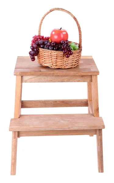 Cesta de mimbre con frutas, en una pequeña escalera de madera, aislada en blanco —  Fotos de Stock