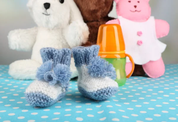 Composición con botines de ganchillo para bebé, biberón, juguete y otras cosas sobre fondo de color — Foto de Stock