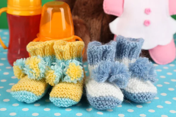 Composición con botines de ganchillo para bebé, biberón, juguete y otras cosas sobre fondo de color — Foto de Stock