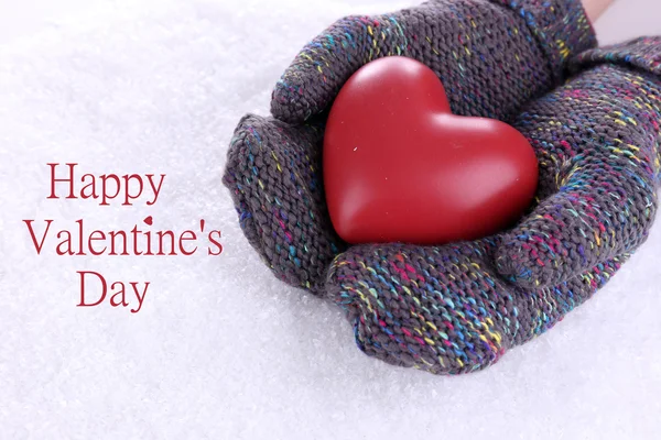 Female hands in mittens with heart on snow background — Stock Photo, Image