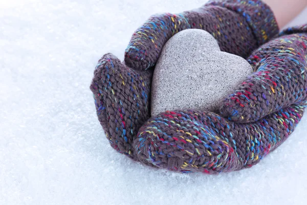 Female hands in mittens with heart on snow background — Stock Photo, Image